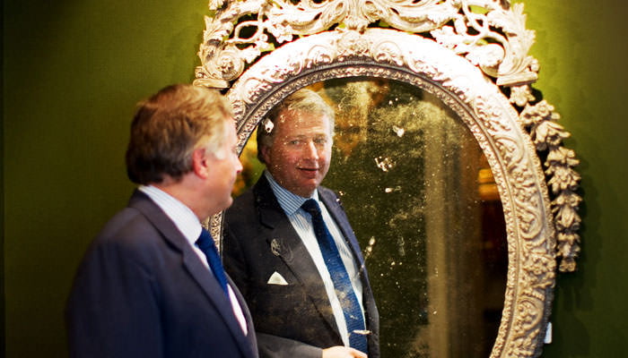 CEO of antques company photographed with antique mirror in Mayfair showroom