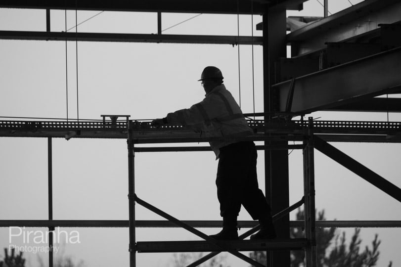 Black and white photograph of building contractor on scaffolding hard at work