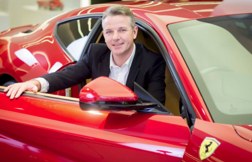 PR photograph of CEO of HR Owen sitting in Ferrari car in London showroom