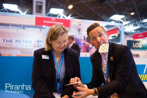 Magician at company trade stand demonstrating trick to guest