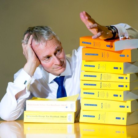 Photograph for PR purposes of accountant with piles of books of legislation