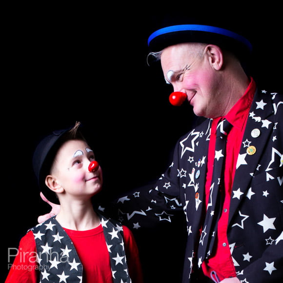 Clown father with son posing for photograph