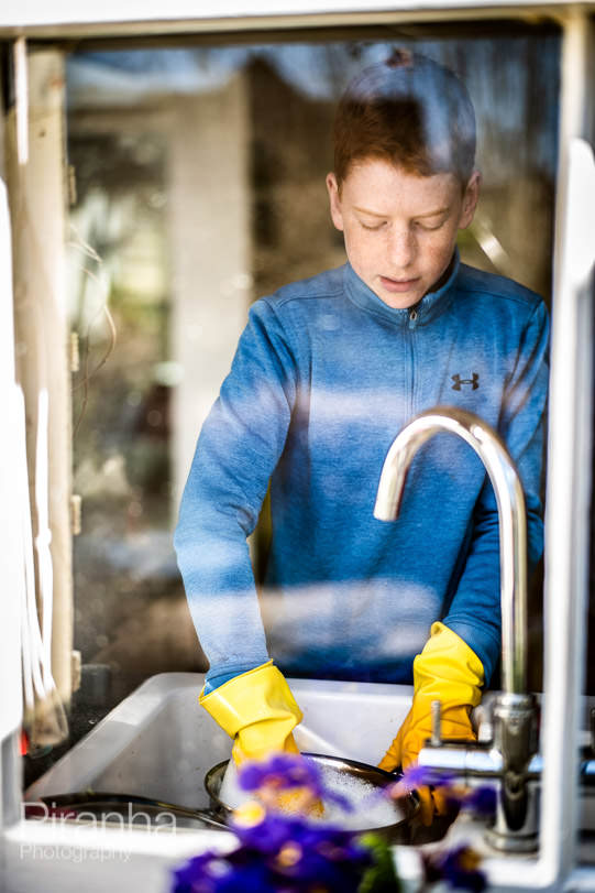 Photograph of teenager washing up at home during lockdown.