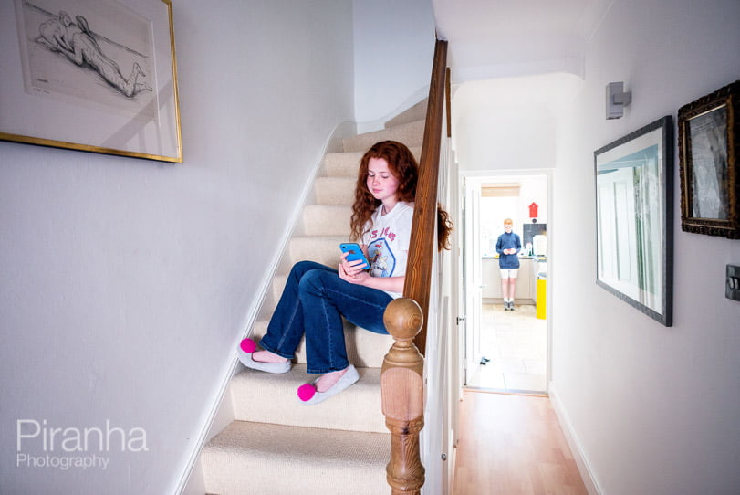 Teenager photographed checking phone on stairs at home