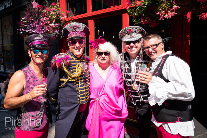 A group of people attending the Pride in London event, standing in front of a pub.