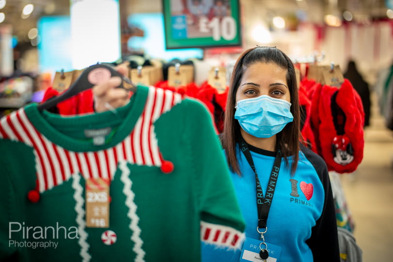 shop assistant offering customer Christmas jumper to buy