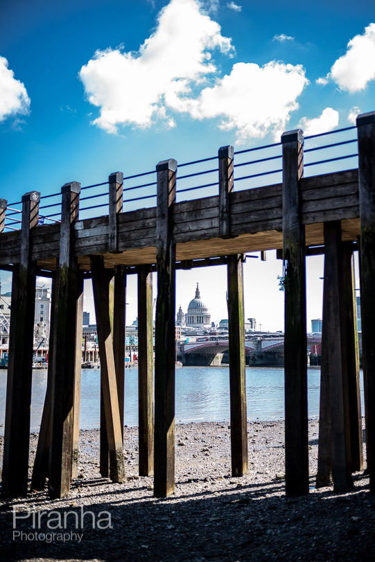 Photography looking up at the City of London from the beach next to the Thames