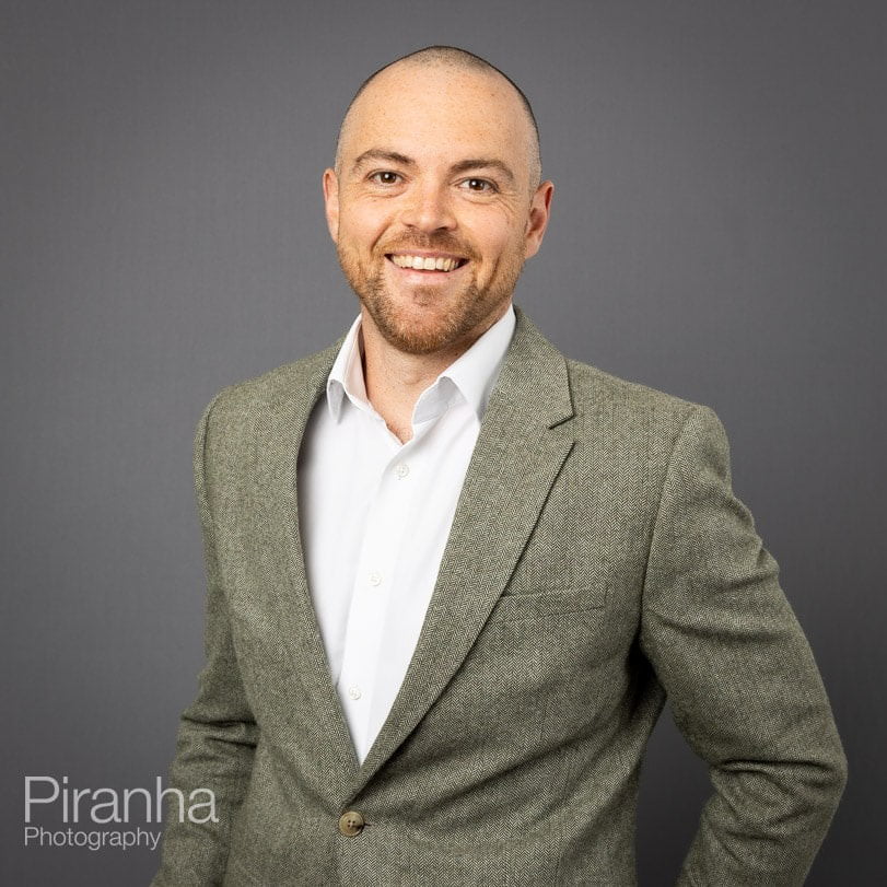 Corporate portrait photograph taken with grey background.
